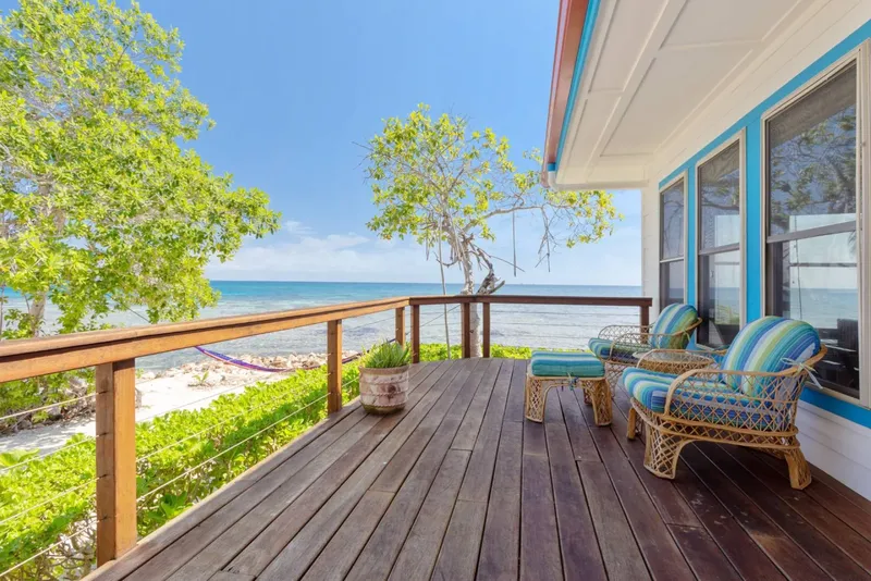 Terrasse en bois avec mobilier, vue sur mer et végétation tropicale