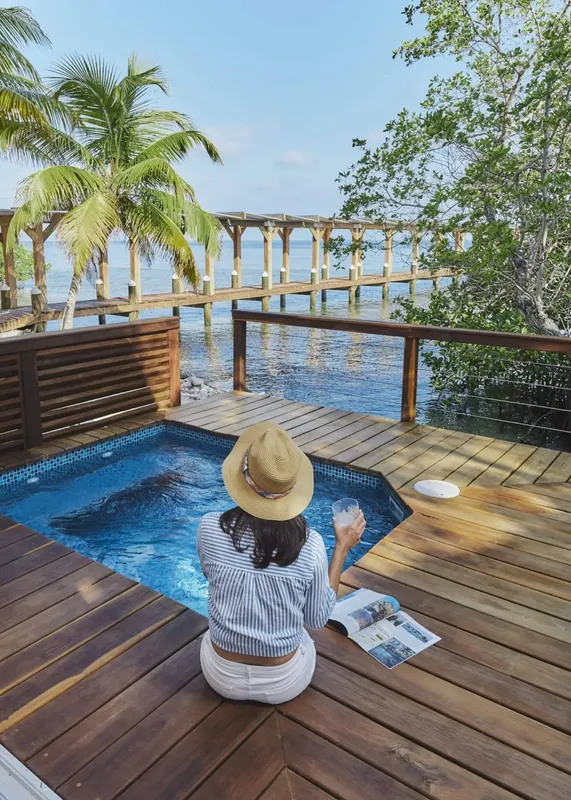 Une personne lit un livre au bord d'une piscine avec vue sur la mer