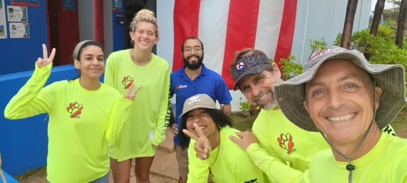 Groupe de personnes souriantes posant devant un bâtiment coloré en extérieur