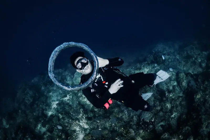 Plongeur souriant manipule un cercle sous l'eau au milieu du récif