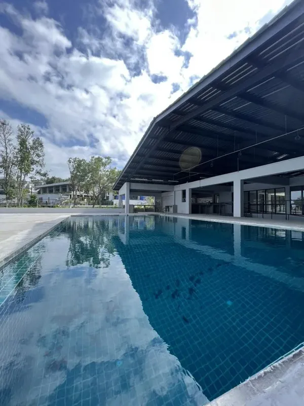 Piscine rectangulaire bleue avec bâtiment blanc et ciel nuageux