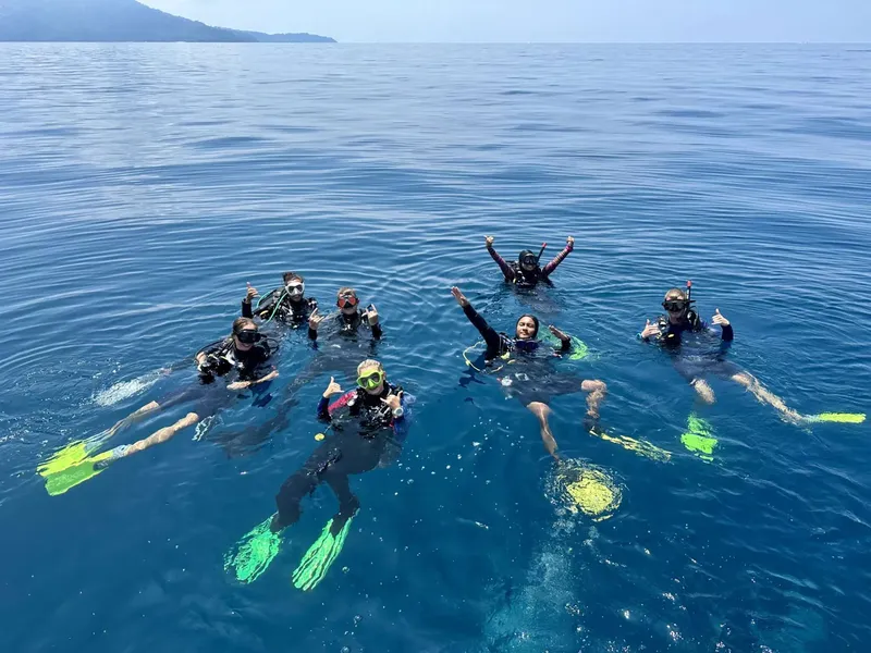 Groupe de plongeurs souriants flottant à la surface de l'eau bleue