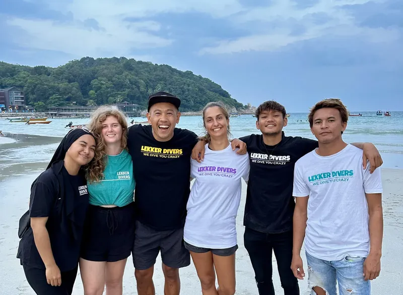 Groupe de cinq personnes souriantes sur une plage ensoleillée