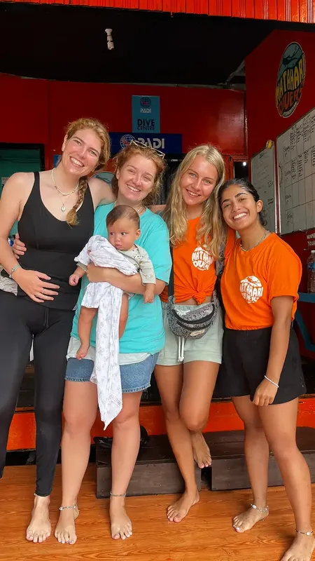 Quatre femmes souriantes et un bébé se tiennent devant un centre