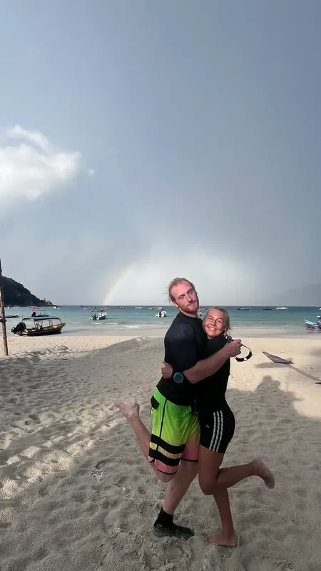 Deux personnes souriantes se prennent en photo sur une plage ensoleillée