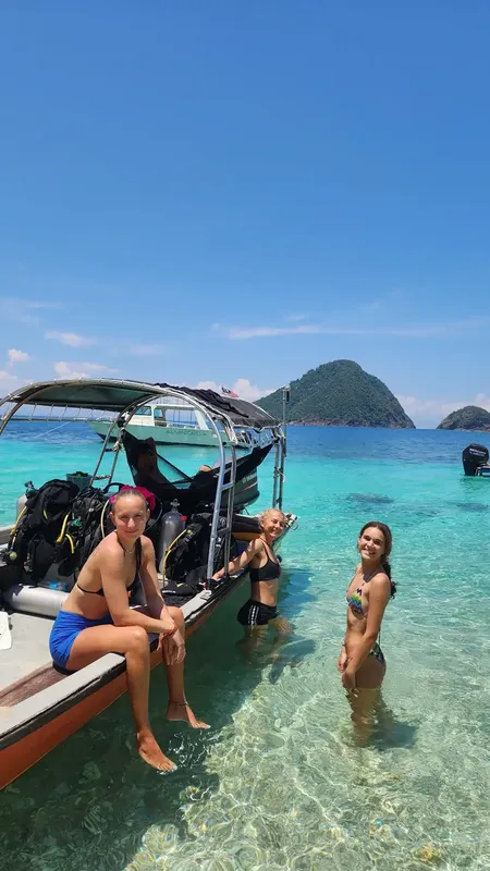 Trois femmes sourient sur un bateau de plongée en mer turquoise