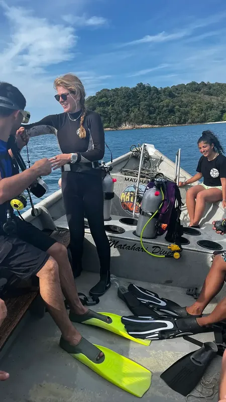 Plongueurs sur un bateau pneumatique, équipement visible, direction une île