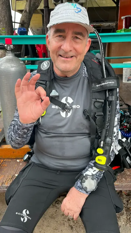 Plongeur souriant salue avec la main, équipé prêt à plonger