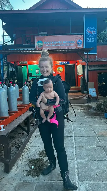 Femme en combinaison de plongée tenant un bébé devant un centre
