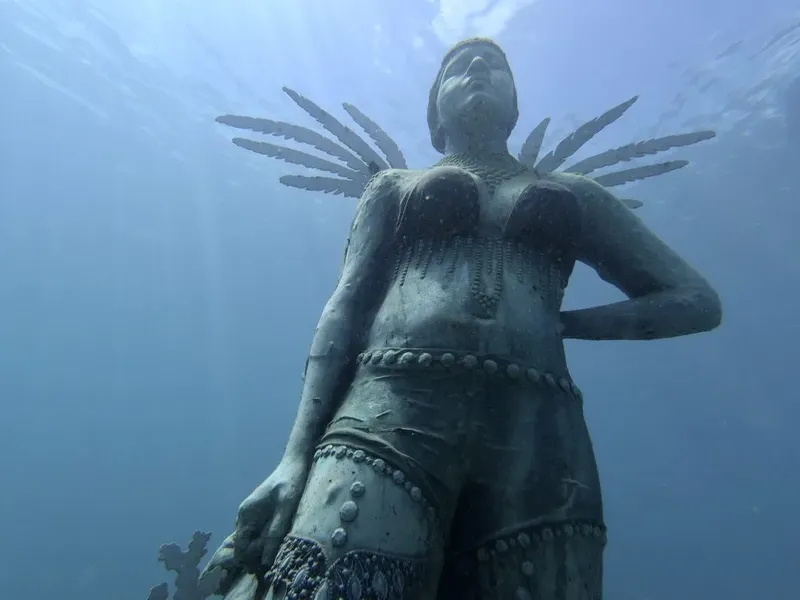 Statue sous-marine d'une femme avec des ailes, lumière bleutée