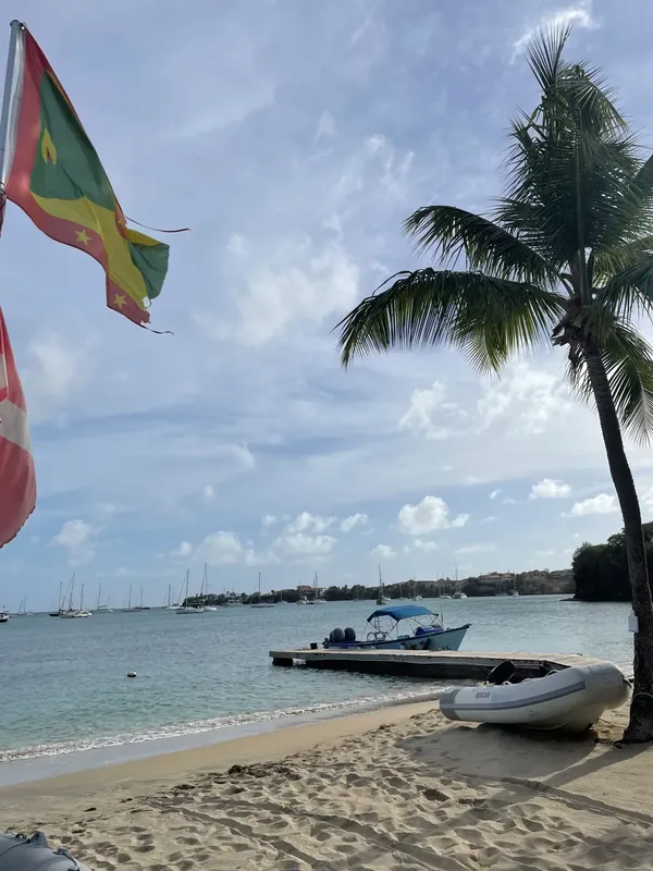 Plage tropicale avec bateaux amarrés et drapeaux flottant au vent