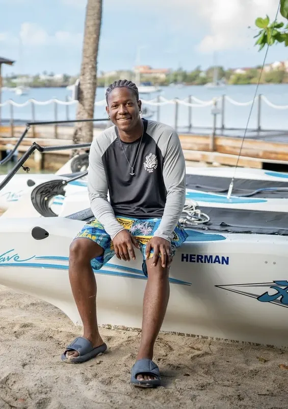 Un homme souriant assis sur la proue d'un bateau blanc