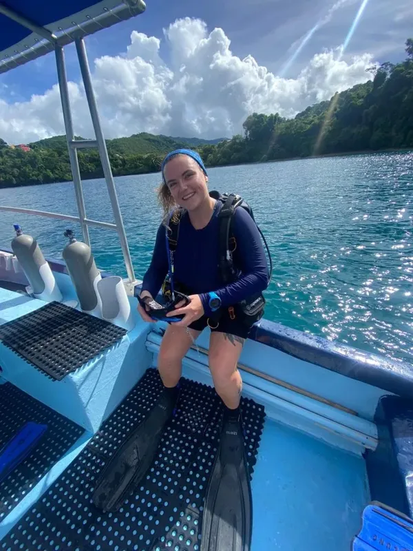 Plongeuse souriante à bord d'un bateau avec son équipement complet