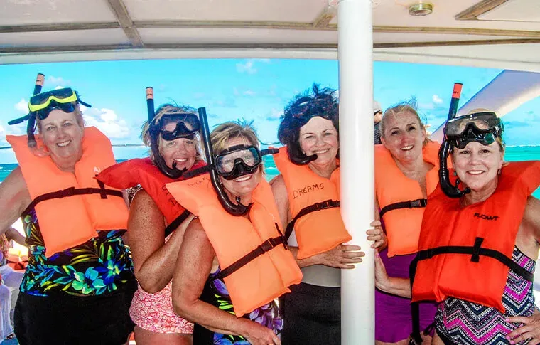 Groupe de femmes souriantes avec gilets et masques de snorkeling à bord