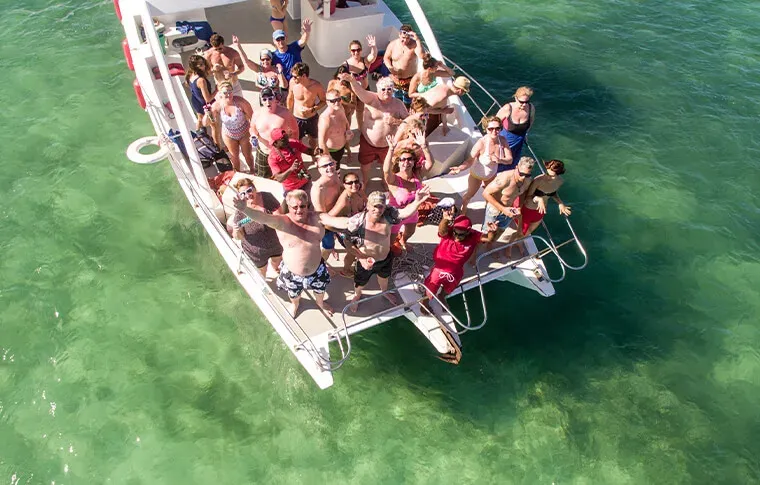 Groupe de personnes souriantes sur un catamaran en mer turquoise