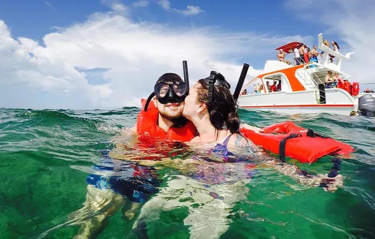 Couple de plongeurs s'embrasse en surface près d'un bateau de plongée