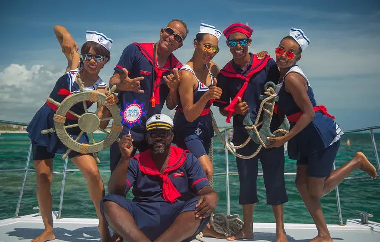 Groupe de personnes souriantes en tenue de marin sur un bateau