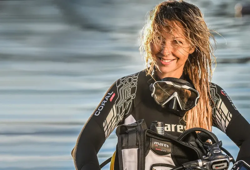 femme souriante en combinaison de plongée avec masque et gilet stabilisateur