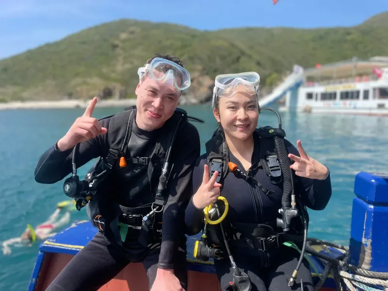 Deux plongeurs souriants en combinaison, masques et détendeurs sur un bateau