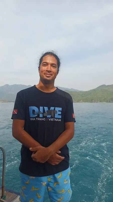 homme souriant sur un bateau en mer avec des montagnes