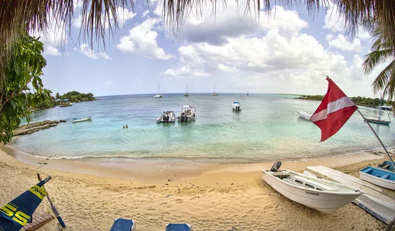 Plage tropicale avec bateaux amarrés et drapeau de plongée au vent