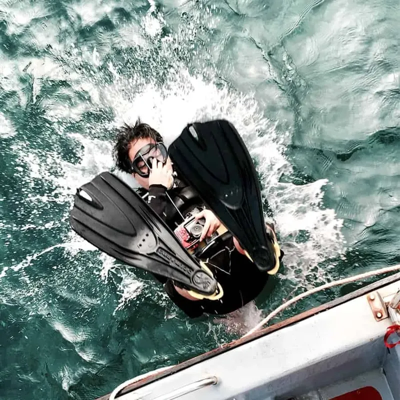 Plongeur équipé s'apprête à entrer dans l'eau depuis un bateau