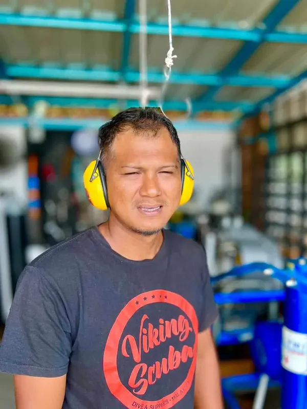 Homme souriant portant un casque et un t-shirt avec un logo