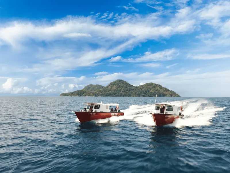 deux bateaux à moteur rouges naviguant en mer vers une île