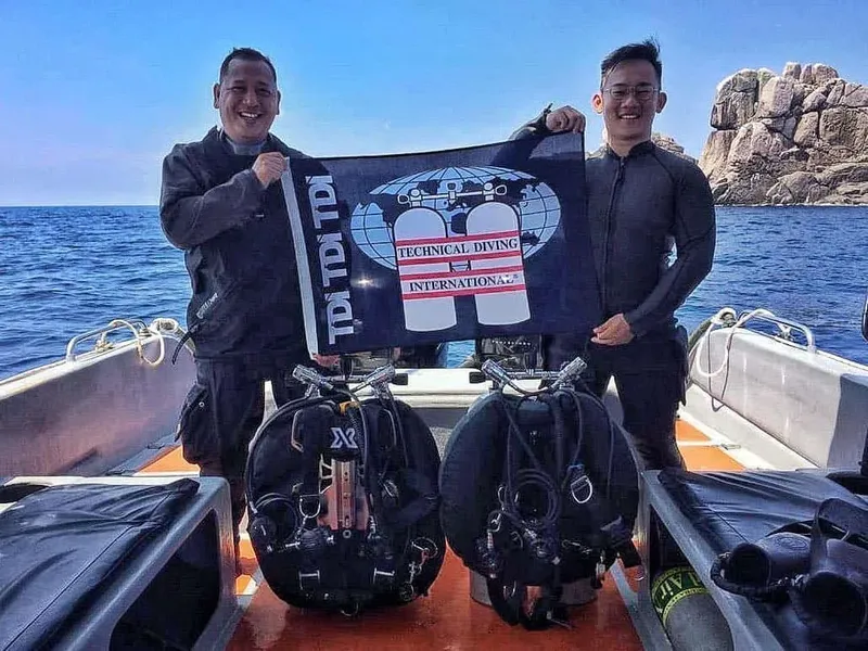 deux plongeurs sur un bateau tenant un drapeau TDI avec du matériel