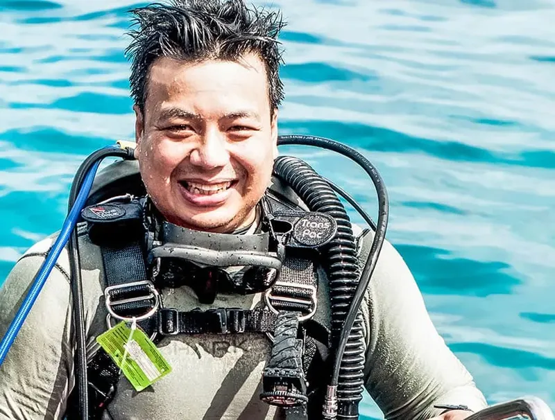 Plongeur souriant avec son équipement complet, prêt pour une immersion