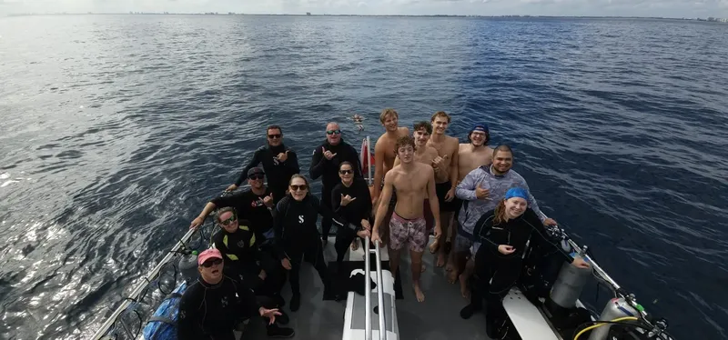 Groupe de plongeurs souriants sur un bateau en mer, ambiance conviviale