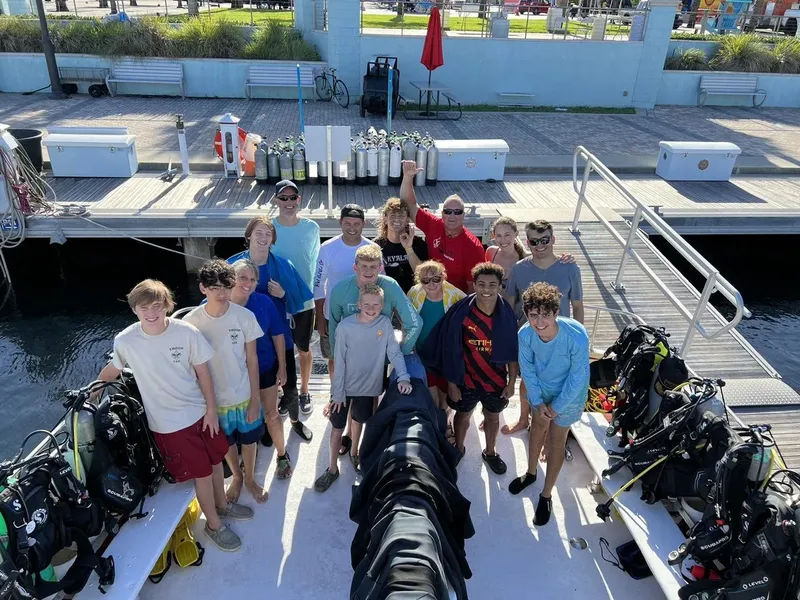 Groupe de plongeurs souriants sur un bateau avec équipement complet