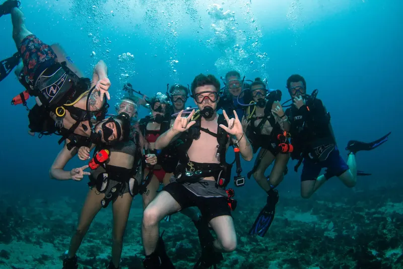 Groupe de plongeurs souriants faisant des signes de la main sous l'eau