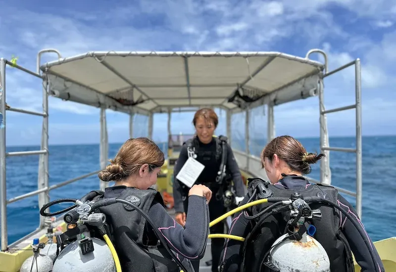Trois personnes équipées pour la plongée sur un bateau en mer