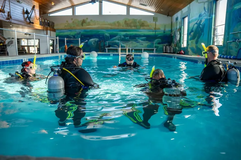 Cours de plongée en piscine avec plusieurs participants équipés