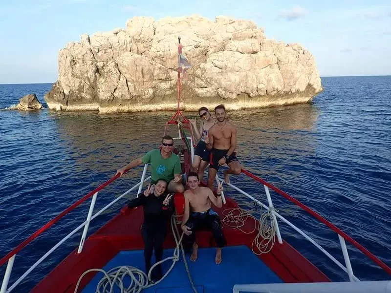 Groupe de personnes souriantes sur la proue d'un bateau en mer