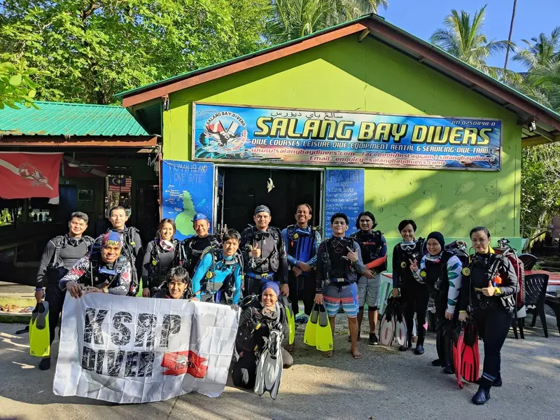 Groupe de plongeurs souriants devant le centre de plongée Salang Bay