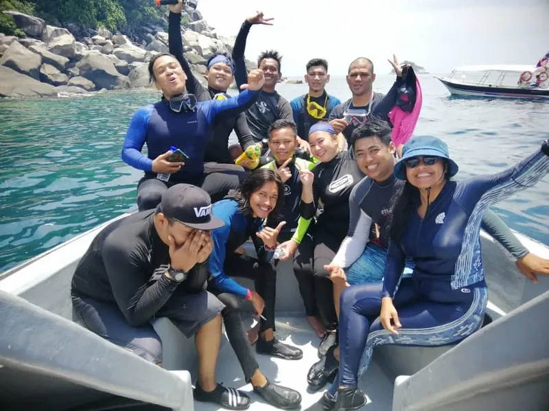 Groupe de personnes souriantes en combinaison de plongée sur un bateau