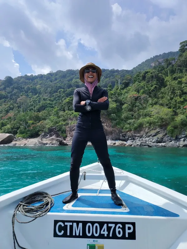Plongeuse en combinaison noire se tient debout sur un bateau blanc