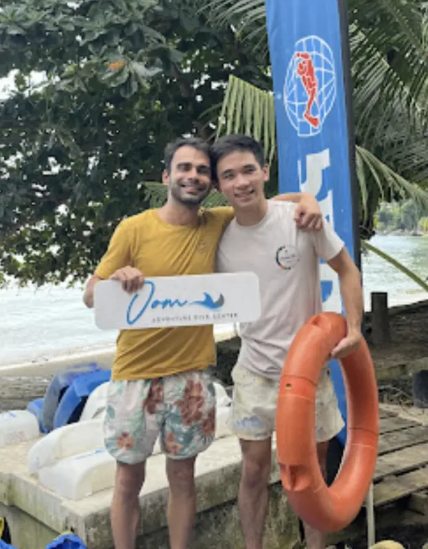 Deux hommes souriants posent sur un quai avec une bouée