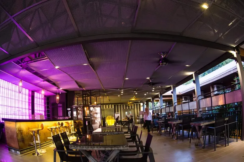 Espace détente avec tables, chaises, bar et éclairage coloré violet