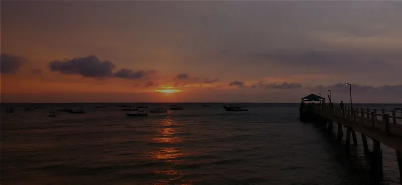 Coucher de soleil sur la mer avec ponton et quelques bateaux