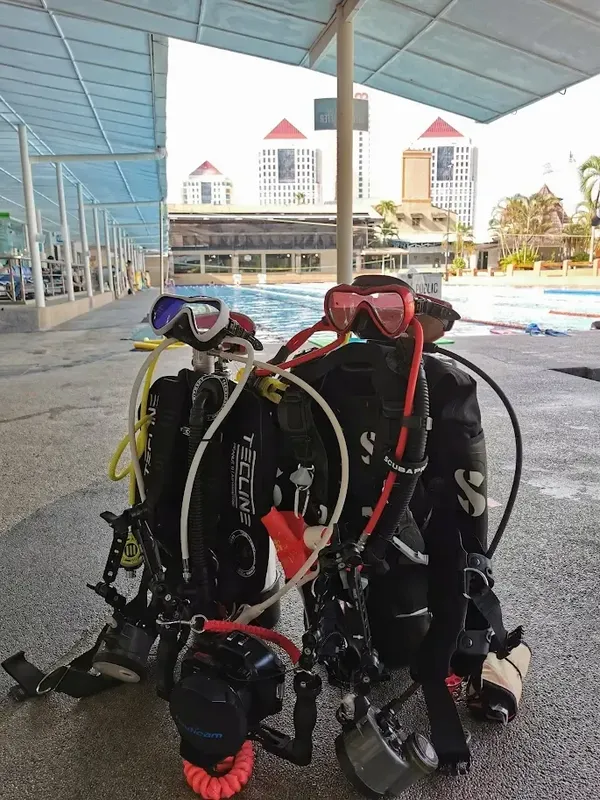 Deux plongeurs équipés près d'une piscine avec bâtiments en arrière-plan