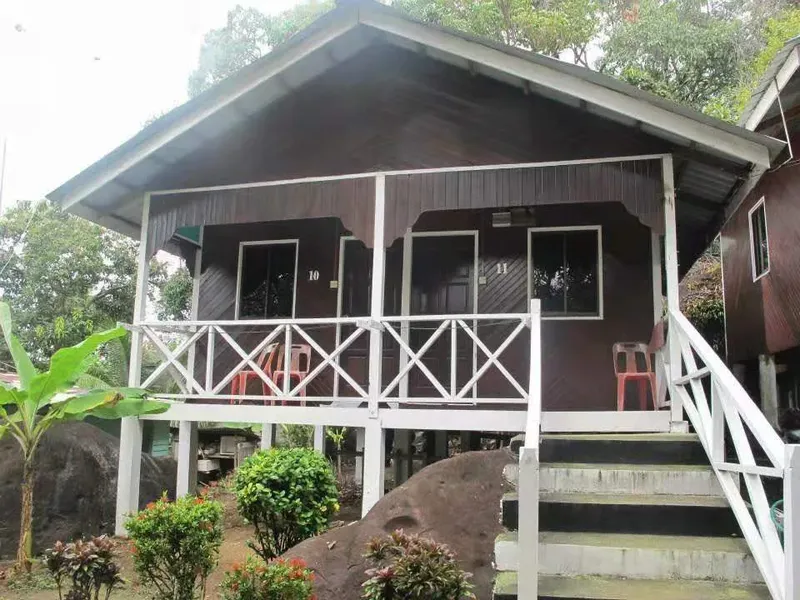 Petite maison en bois sur pilotis avec terrasse et végétation tropicale