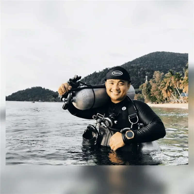 Plongeur souriant équipé de son matériel près d'une plage