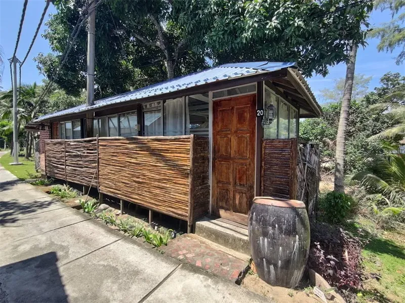 Petite construction en bois avec porte et fenêtres, entourée de végétation