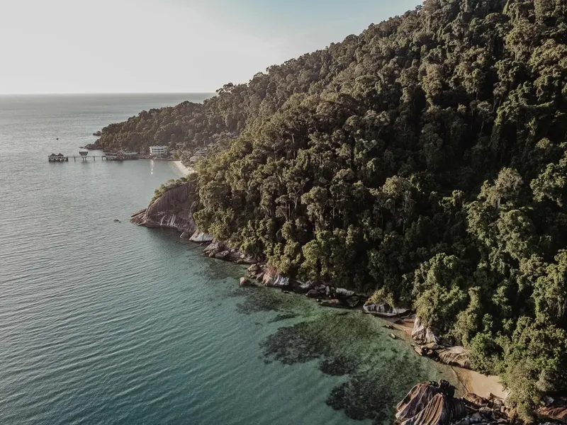Côte rocheuse et forêt tropicale surplombant une mer turquoise calme