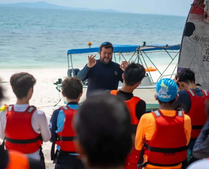 Instructeur expliquant les consignes de sécurité à un groupe de plongeurs sur une plage