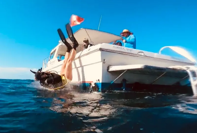 Plongeur entrant dans l'eau depuis un bateau de plongée en mer