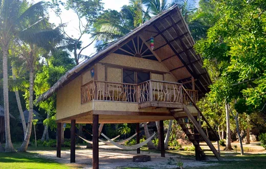 Petite maison sur pilotis avec hamac dans un cadre tropical